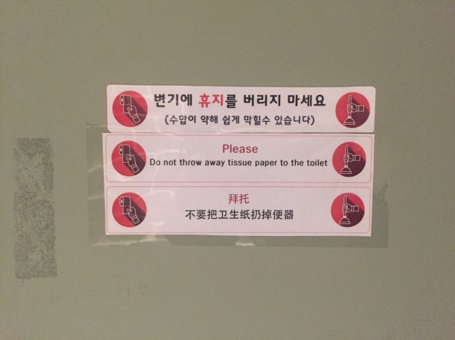 A public bathroom stall in Seoul has a sign that asks users not to flush waste paper down the toilet, and to discard them in trash cans instead, as water pressure is low. (Claire Lee/The Korea Herald)