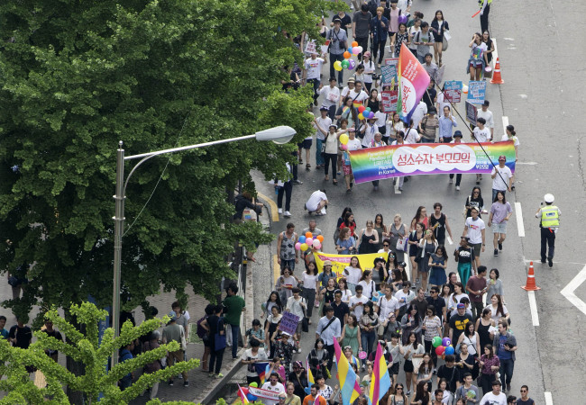 Participants march through central Seoul at the Pride Parade, waving rainbow-colored fans and flags, Saturday. (Yonhap)