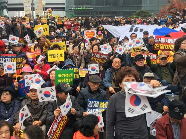 People participating in a pro-Park rally hold signs and national flag in front of Seoul Station in central Seoul Saturday. (Ock Hyun-ju/The Korea Herald)