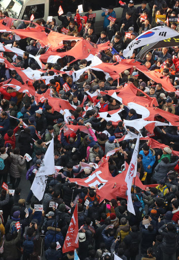 Protestors tear apart the flag of the ruling Saenuri Party during the rally held at 2 p.m. near its head office in southwestern Seoul. (Yonhap)