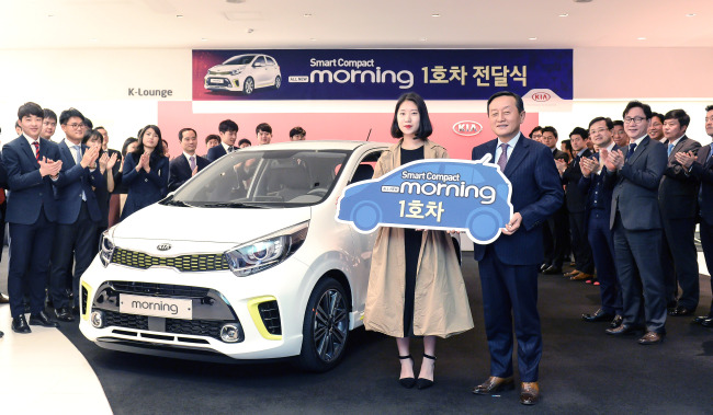 Choi Soo-bin (center), the first customer to buy Kia Motors’ All New Morning compact car, poses with company officials during a ceremony celebrating the vehicle’s sales launch at the domestic sales division office in Apgujeong-dong, Seoul on Friday. (Hyundai Motor Company)