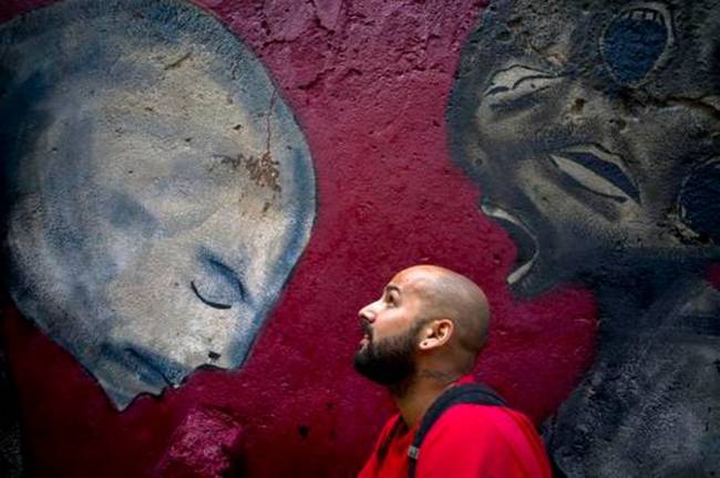 In this Feb. 9 photo, graffiti artist Yulier Rodriguez Perez poses with one of his works, painted on a wall in Old Havana, Cuba. (AP-Yonhap)