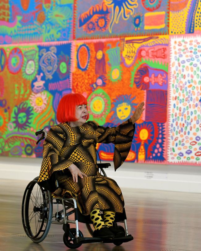 Japanese artist Yayoi Kusama waves at a photo session during a press preview of her exhibition titled 