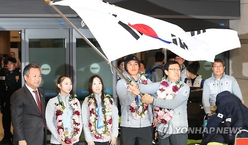 Kim Sang-hang (R), head of the South Korean delegation to the Sapporo Asian Winter Games, and Kim Magnus, cross-country skiing gold medalist, wave the national flag at Incheon International Airport after returning from the competition on Feb. 27, 2017. (Yonhap)