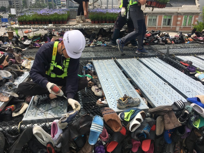 Workers hang worn-out shoes on Shoes Tree on Seoullo 7017, Seoul’s soon-to-open pedestrian-friendly park, near Seoul Station on Tuesday. (Kim Da-sol/The Korea Herald)