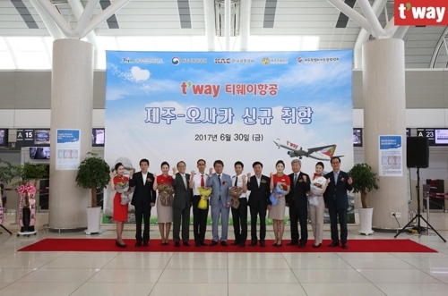 The company`s CEO Jeong Hong-geun (sixth from left) and employees celebrate the opening of the Jeju Island-Osaka route at Jeju International Airport on June 30, 2017. (T`way Air)