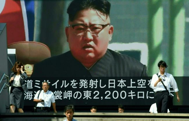 Pedestrians walk in front of a large video screen in Tokyo broadcasting a news report showing North Korean leader Kim Jong-un, following a North Korean missile test that passed over Japan on Friday. (AFP-Yonhap)
