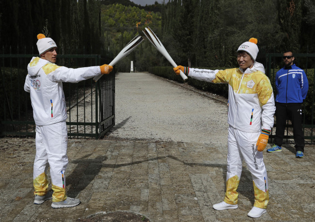 South Korean former soccer player Park Ji-Sung (right) receives flame from former torch bearer Greek cross-country skier Apostolos Angelis (left) during the lighting ceremony of the Olympic flame in Ancient Olympia, southwestern Greece, on Tuesday. (AP-Yonhap)