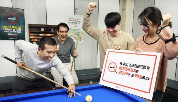 Campaigners hold a no-smoking sign at a pool hall promoting the smoking ban which came into effect Sunday making it illegal to smoke in indoor sports and leisure facilities.  (Ministry of Health & Welfare)