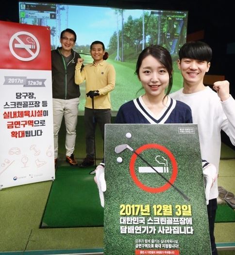 Campaigners hold a no-smoking sign at a screren golf studio promoting the smoking ban which came into effect Sunday, making it illegal to smoke in indoor sports and leisure facilities. (Ministry of Health & Welfare)