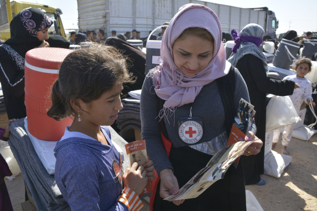 An ICRC worker distributes relief items to an internally displaced person at the Amiryat Al-Someed camp in Anbar province, Iraq. (ICRC)