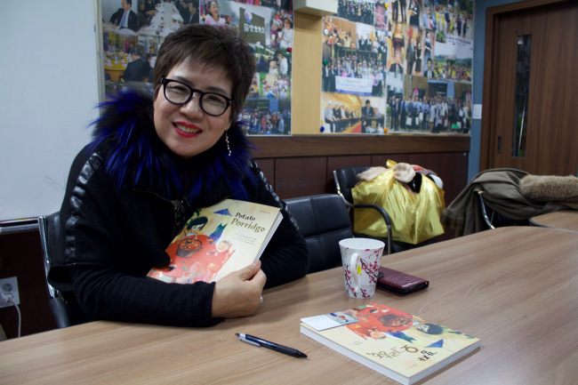 Park Kyung-hee poses with the English version of her book “Potato Porridge.” (Sylvia Lee/The Korea Herald)