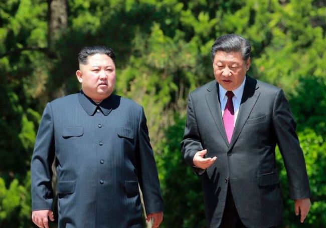 In a file photo taken on May 8, Chinese President Xi Jinping, right, takes a stroll with North Korean leader Kim Jong-un in Dalian in northeastern China. (Yonhap)