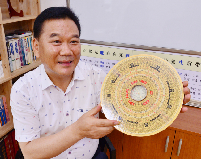 Veteran geomancy consultant Jeon Hang-soo poses with an ancient compass used for divination. (Park Hyun-koo/The Korea Herald)