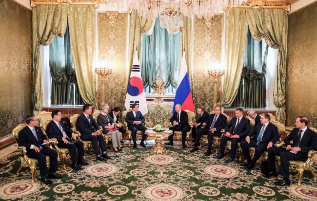 South Korean President Moon Jae-in and Russian counterpart Vladimir Putin, respectively accompanied by their key ministers, sit in an expanded summit on Friday. (Yonhap)