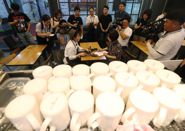 An official from the Ministry of Environment show the press how clamp-downs on coffee businesses are being done at a cafe in Seoul, on Aug.2. (Yonhap)