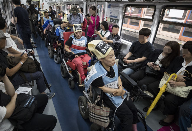 South Koreans with disabilities protest Seoul`s public transportation system, which they claim to be unsafe and non-inclusive, inside a Seoul Metro train in July (Yonhap)