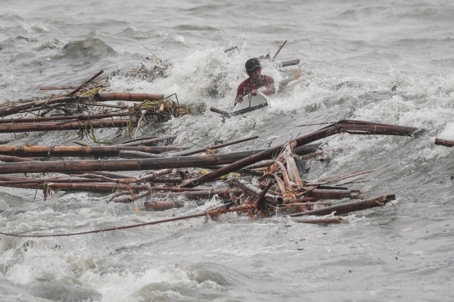 A man is hit by a wave while attempting to recover salvageable materials in Manila Bay, Manila, Philippines, Saturday. (Yonhap)