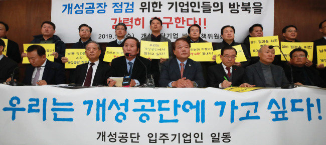 Members of a committee of business owners, who operated in Kaesong industrial complex, hold placard reading, 