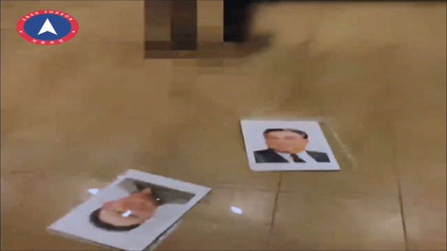 A screenshot of a video published on March 20 by Free Joseon shows a man removing portraits of North Korean leaders from the wall. (YouTube)