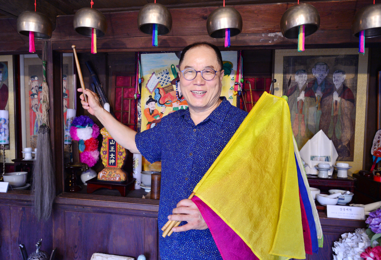 Yang Jong-sung explains the flags and bells used by shamans at the Museum of Shamanism in Seoul's Eunpyeong-gu district, Tuesday. (Park Hyun-koo/The Korea Herald)