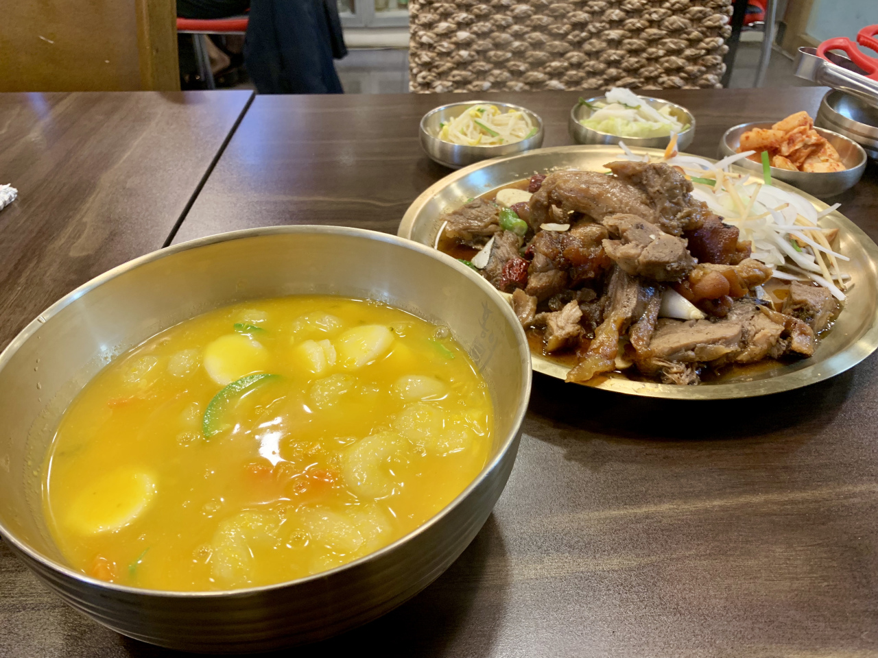 Rice cake soup with ground potato (left) and steamed pig's leg. (Im Eun-byel/The Korea Herald)