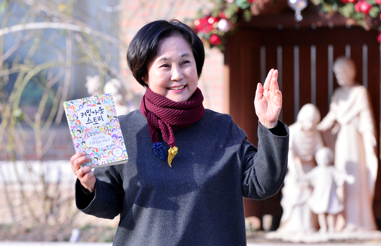 Hong Jung-seun poses for a photo on Jan. 16 in front of a Catholic church in southwestern Seoul while holding a book, titled “Coming Out Story,” which she co-authored with other parents of LGBT people. (Park Hyun-koo/The Korea Herald)