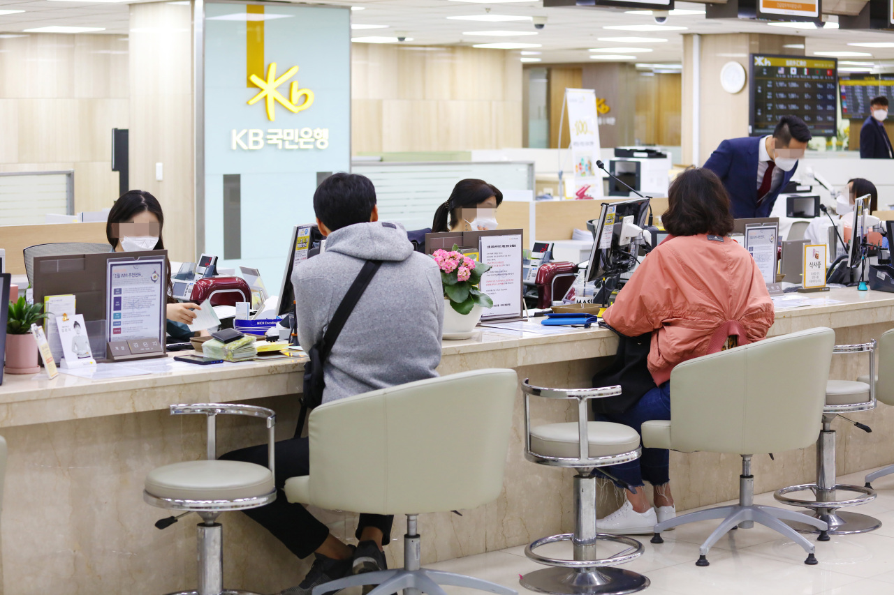 In this photo taken on Jan. 28, KB Kookmin Bank employees wear face masks in front of customers to prevent the spread of coronavirus. (Yonhap)