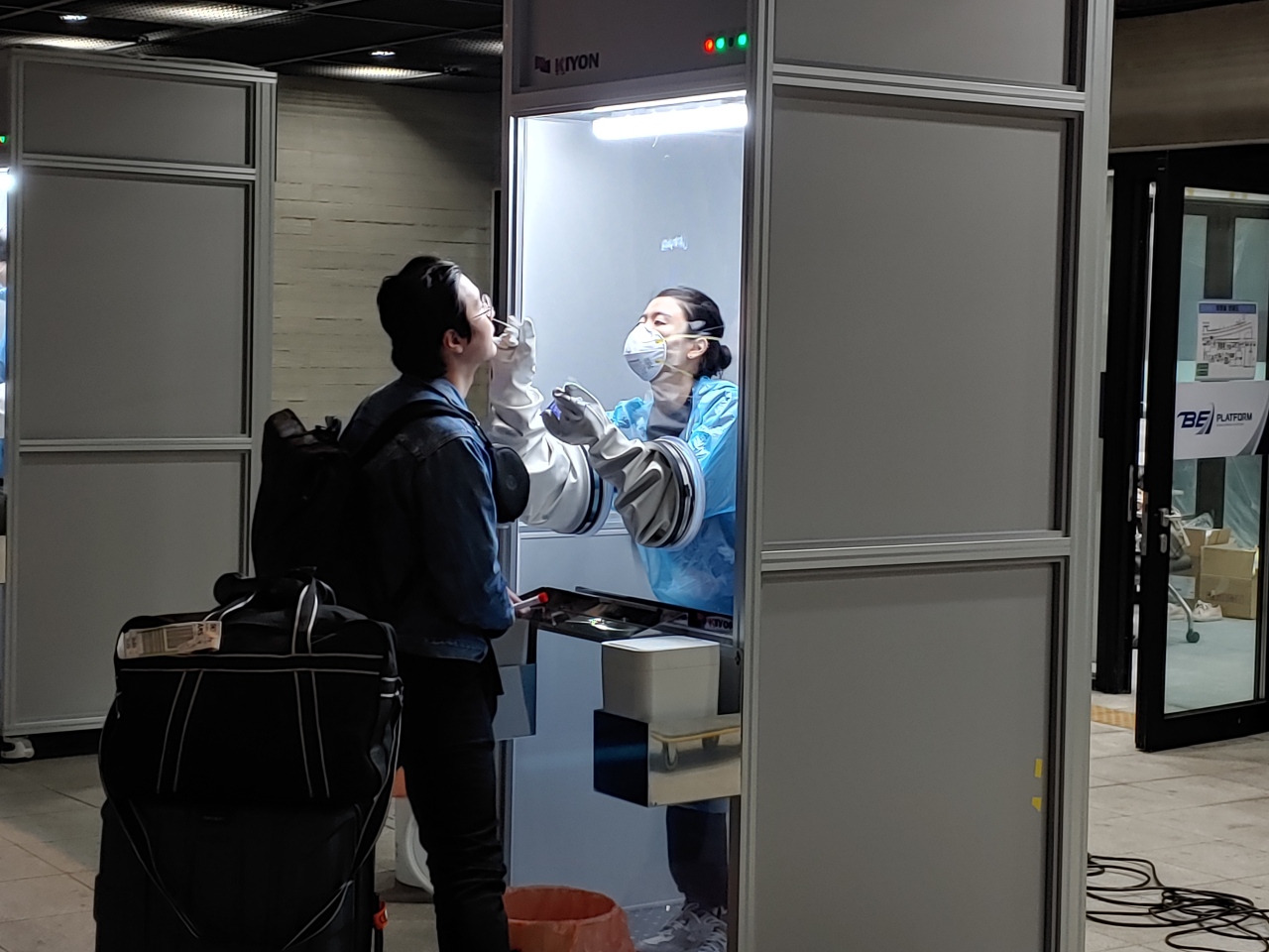 A health care worker conducts nasal swab testing inside the walk-thru testing booth. (Korea Kiyon)
