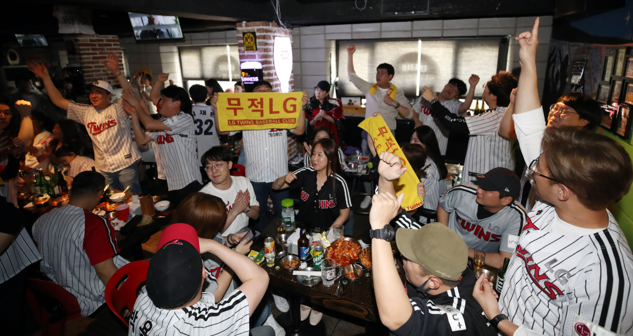 Fans of the LG Twins cheer on the team during the KBO Opening Day, on Tuesday in a pub in Seoul. (Yonhap)
