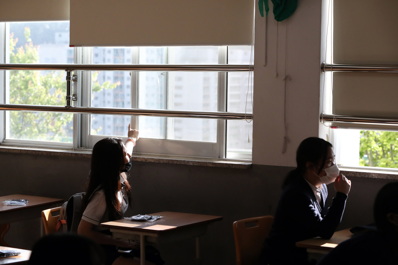 A student opens a classroom window May 20. (Yonhap)