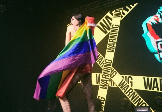 Sunmi poses on stage with a rainbow flag wrapped around her body while performing in Amsterdam. (Sunmi's Instagram)