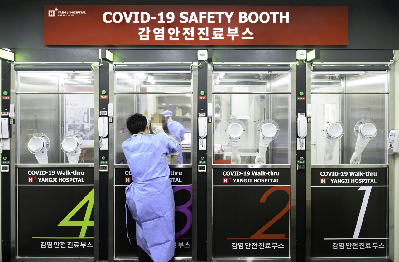 A health care worker at H Plus Yangji Hospital tests a visitor to the patented walk-thru testing facility. (KIPO)