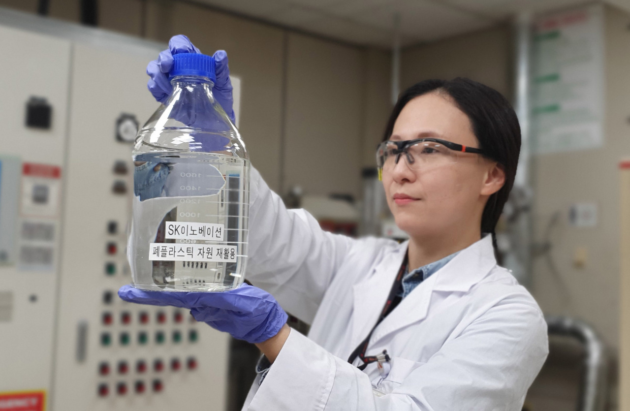 A researcher at SK Innovation Institute of Technology Innovation holds a beaker of solvent extracted from plastic waste. (SK Innovation)