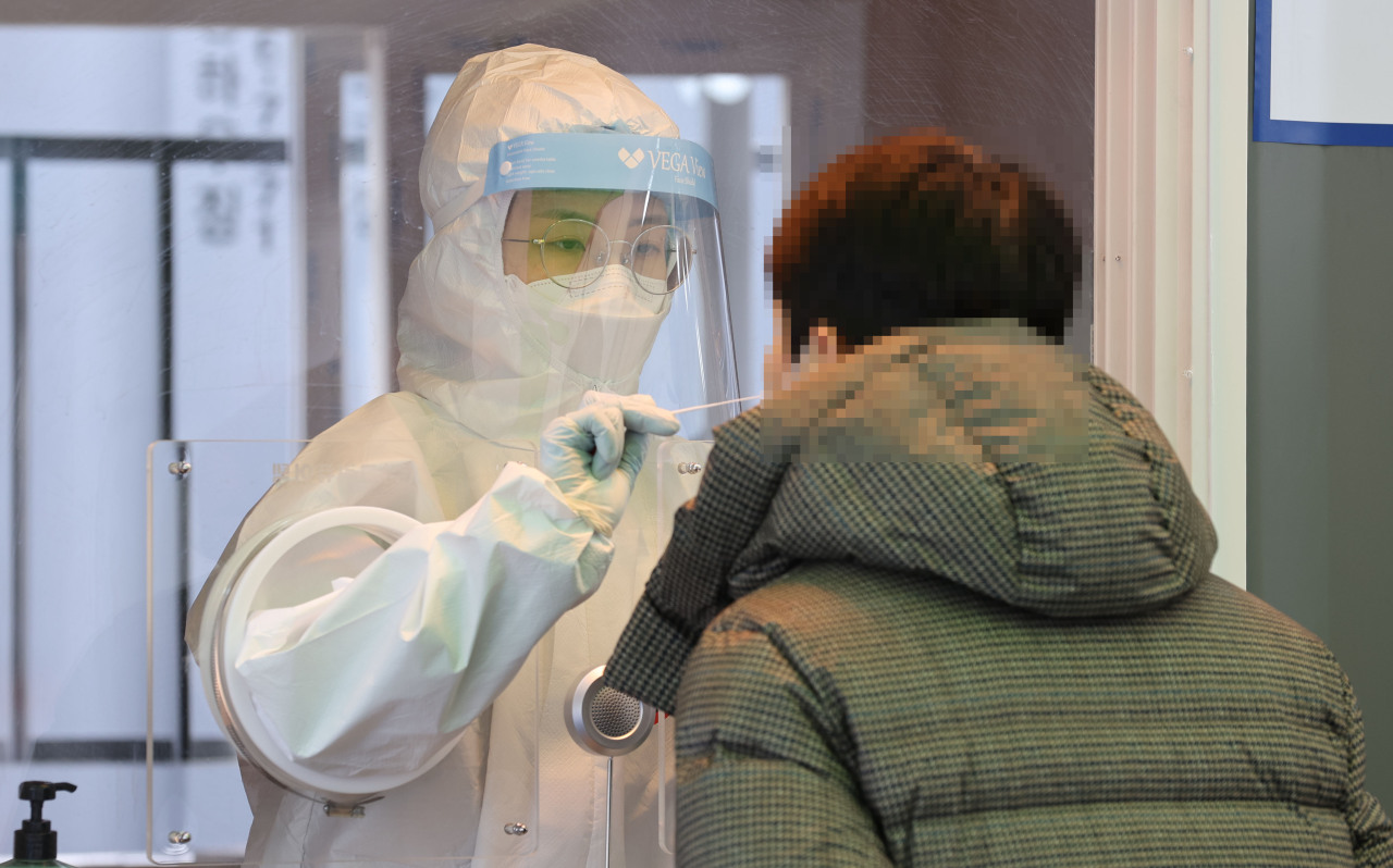 A medical worker collects a swab sample for a coronavirus test at a makeshift COVID-19 screening facility in Seoul on Saturday. (Yonhap)