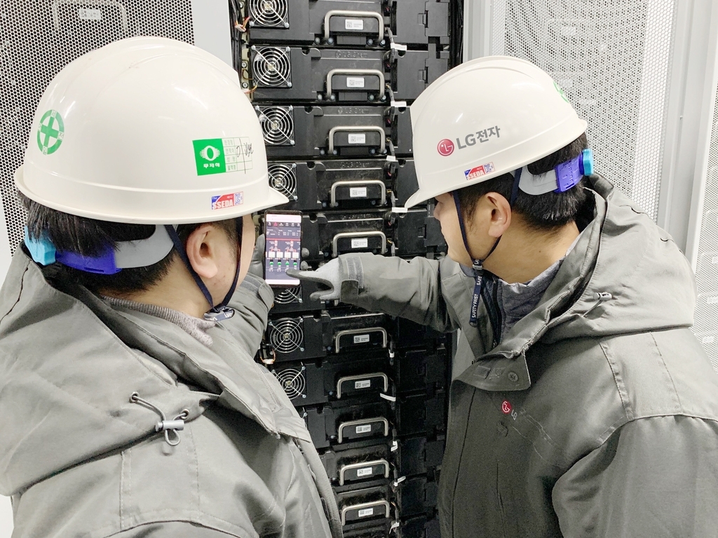 This photo provided by LG Electronics Inc. on Sunday, shows LG workers checking an energy storage system in Anjwa Island, South Jeolla Province, through a smartphone. (LG Electronics Inc.)