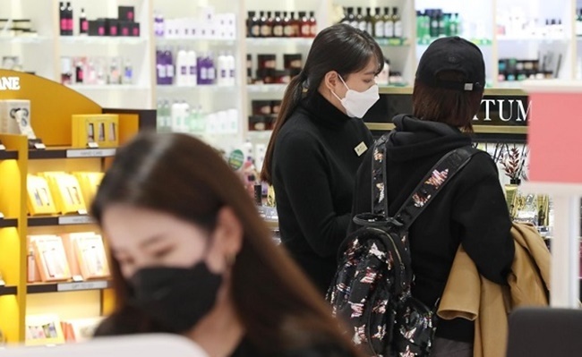 Staff and shoppers look at products at a cosmetics store. (Yonhap)