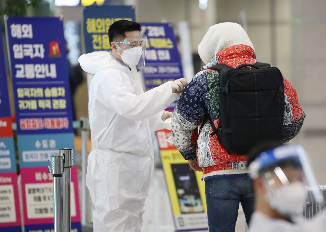 A quarantine official attaches a sticker to the shoulder of a passenger from abroad at Incheon airport, west of Seoul, on Monday. (Yonhap)