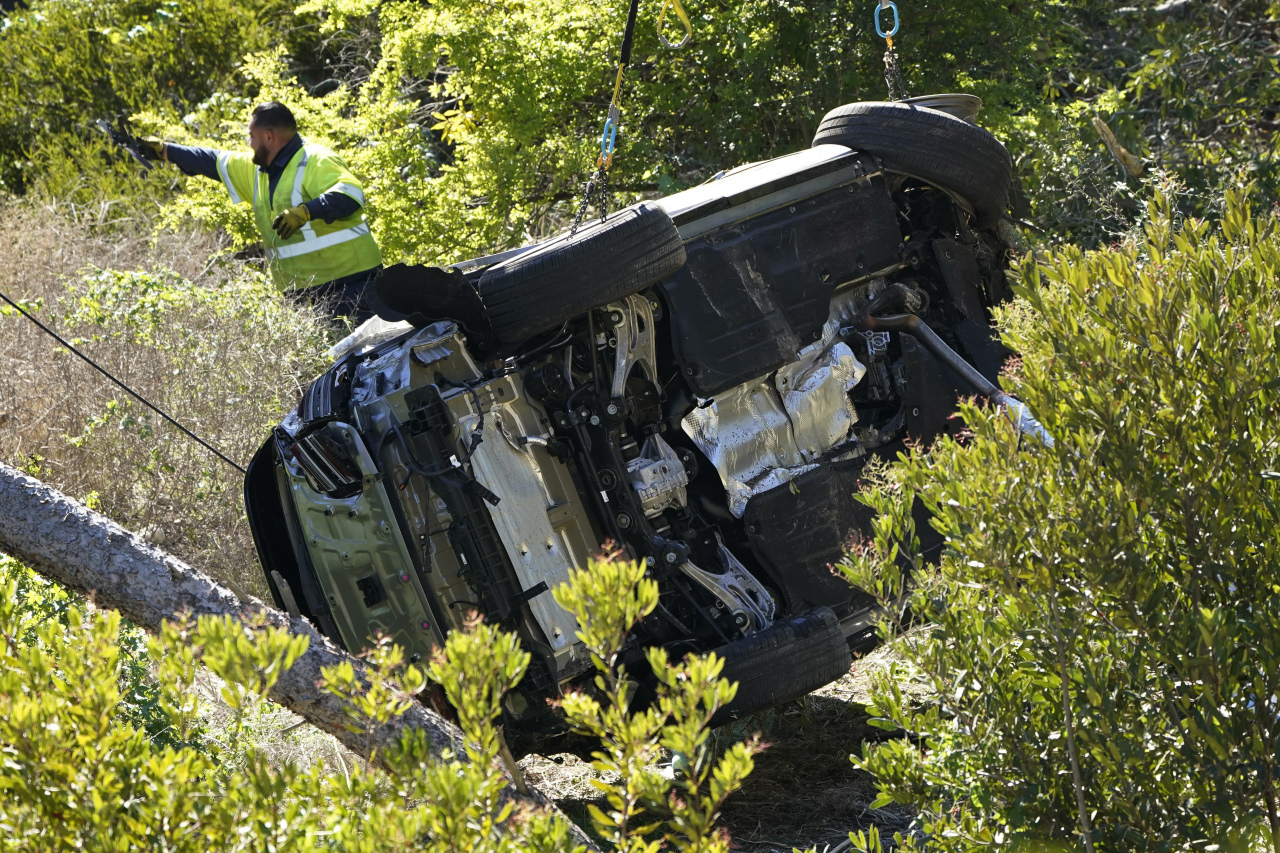 Workers move a vehicle on its side after a rollover accident involving golfer Tiger Woods Tuesday, in Rancho Palos Verdes, Calif., a suburb of Los Angeles. Woods suffered leg injuries in the one-car accident and was undergoing surgery, authorities and his manager said. (AP-Yonhap)