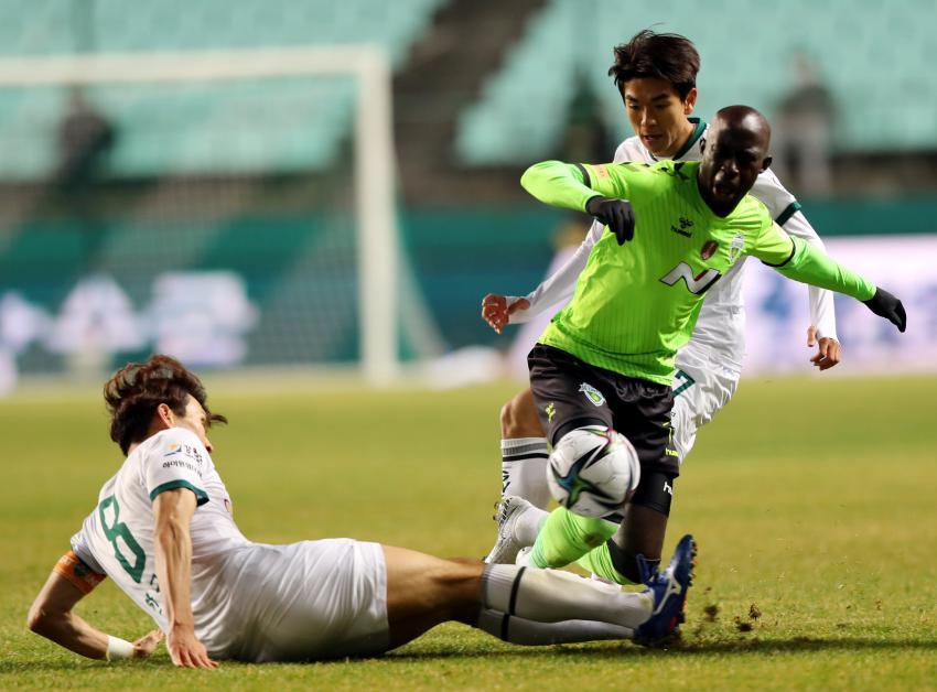 In this file photo from March 9, 2021, Mo Barrow of Jeonbuk Hyundai Motors (R) is tackled by Han Kook-young of Gangwon FC (L) during a K League 1 match at Jeonju World Cup Stadium in Jeonju, 240 kilometers south of Seoul. (Yonhap)