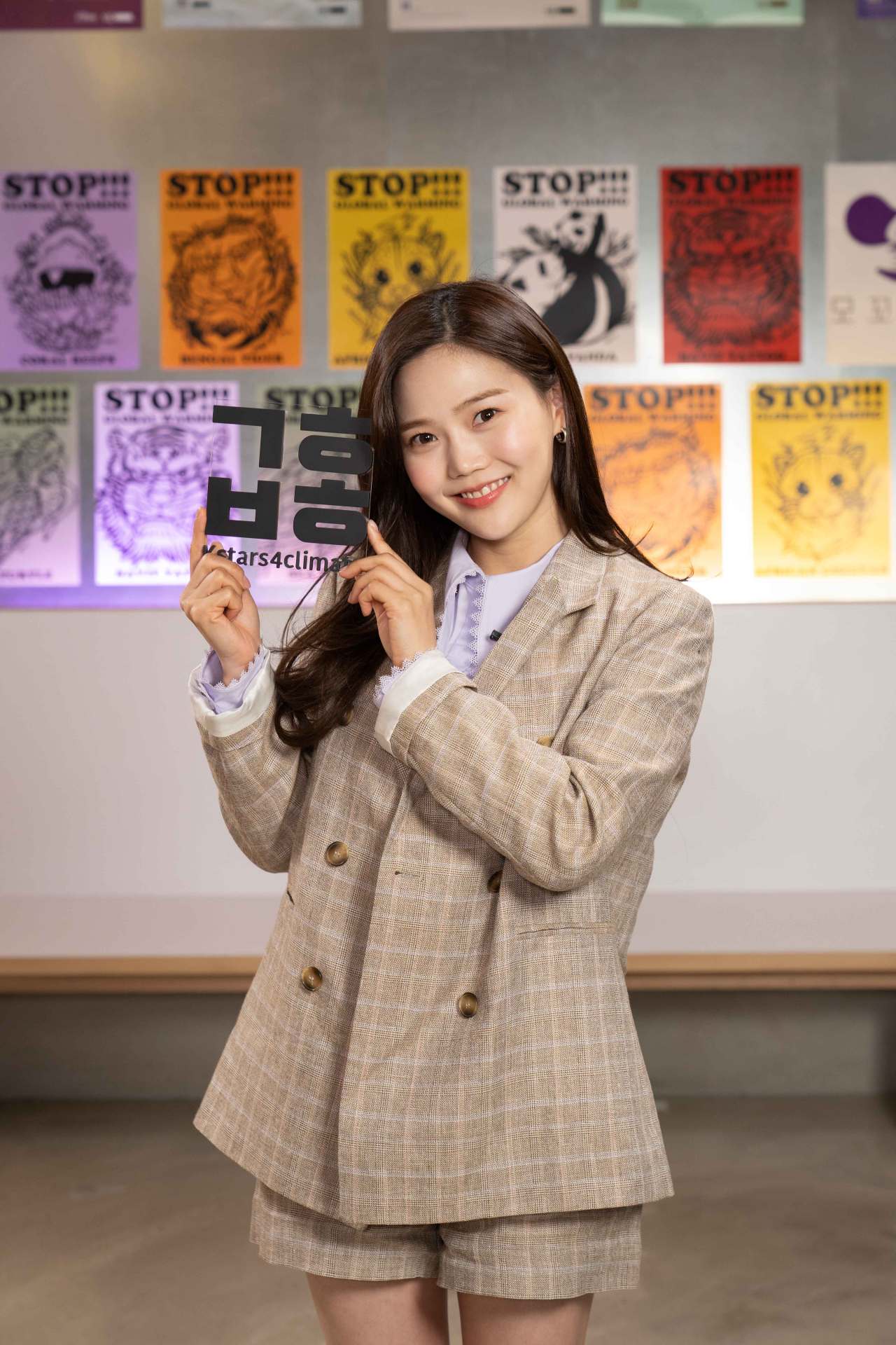 Hyojung from girl band Oh My Girl holds a sign showing the Hangeul abbreviation for 