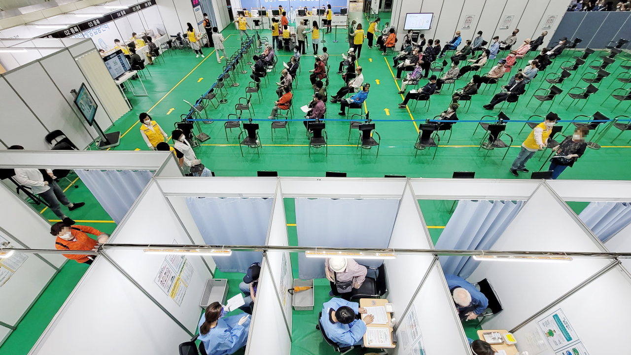 Seoul residents wait in line at a COVID-19 vaccination clinic in Jungnang, a northern district in the city, on Thursday morning. People in their 60s and older are now eligible for vaccination. (Yonhap)