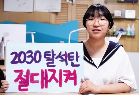 Teenage climate activist Yoon Hyeon-jeong holds up a placard reading “2030 coal-free, keep the promise!” (Lee Sang-sub/The Herald Business)