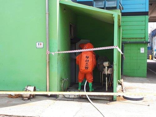 Firefighters in protective gear examine a restroom at a shipyard in the southeastern city of Busan on Saturday, in the photo provided by fire authorities there. (Busan fire authorities)