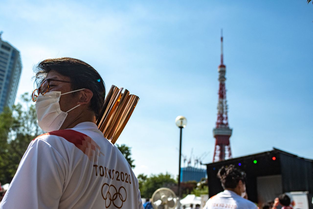 A torchbearer walks past the Tokyo Tower with his Olympic torch the after Olympic flame lighting ceremony at Shiba Park in Tokyo on July 22, 2021, ahead of the Tokyo 2020 Olympic games. (AFP-Yonhap)