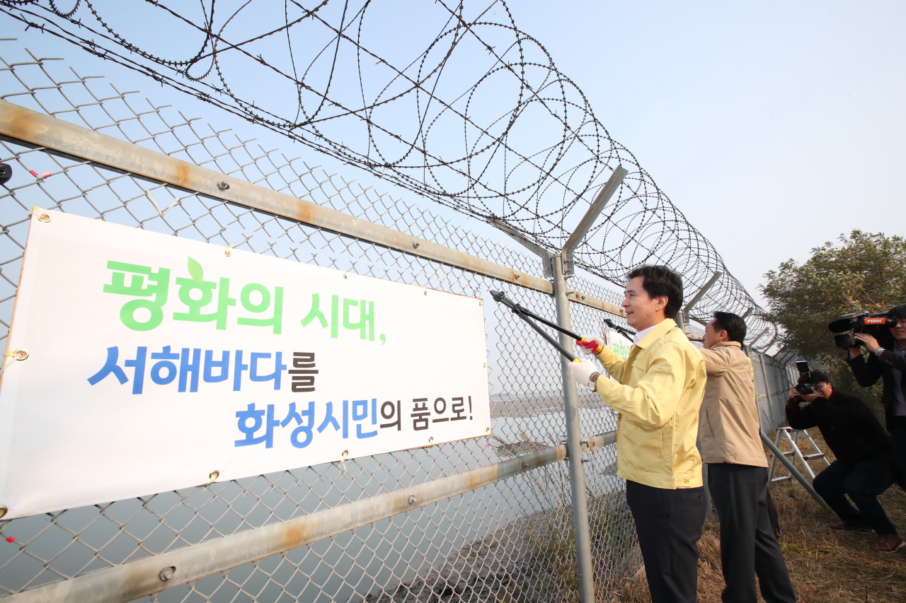 Hwaseong Mayor Seo Cheol-mo (left) leads the demolition of military fences in Seosin-myeon, Hwaseong, allowing for citizens to be able to enjoy the West Sea, in October 2018. (Hwaseong City)