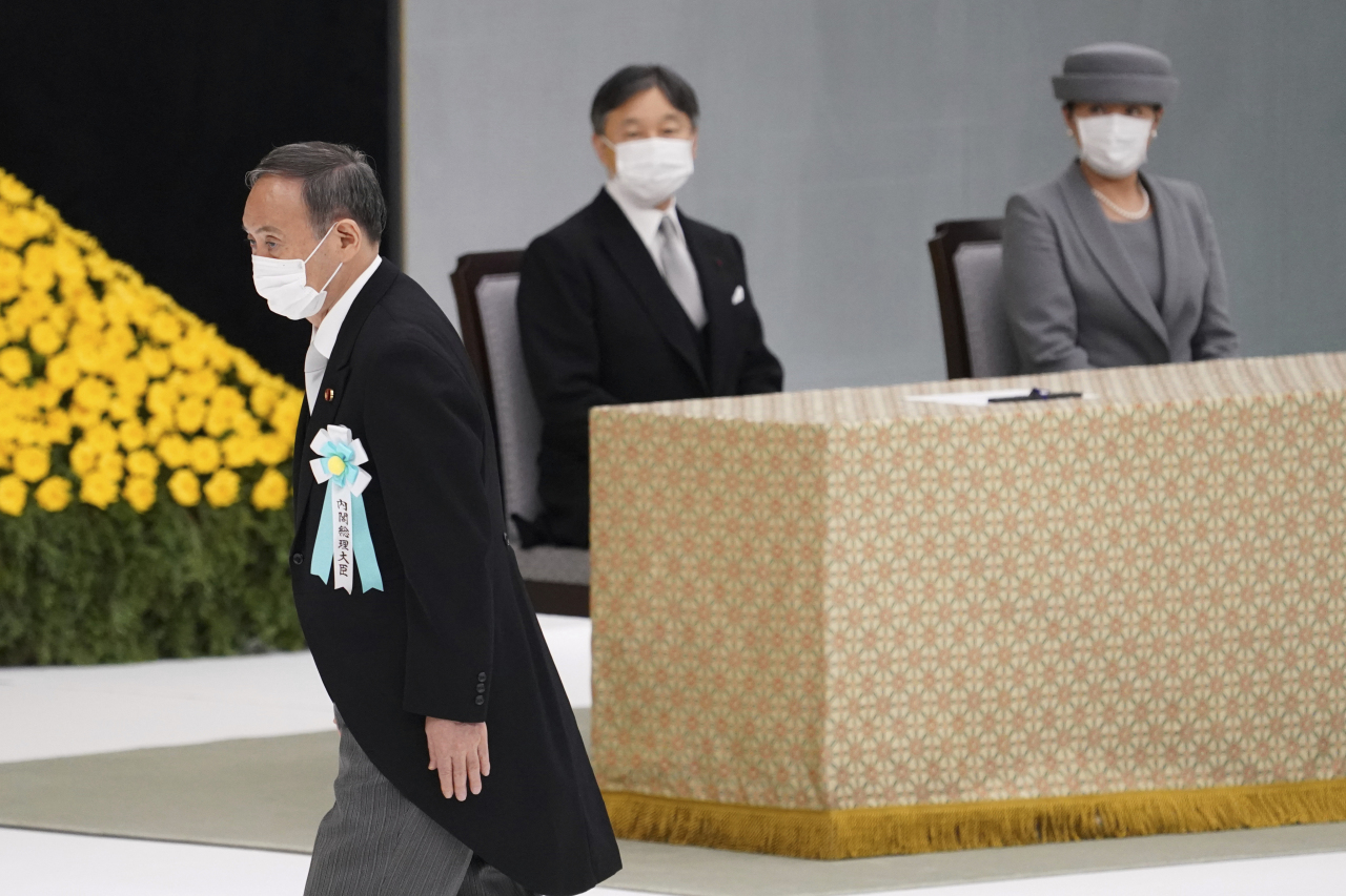 Japanese Prime Minister Yoshihide Suga walks past Japan's Emperor Naruhito and Empress Masako to deliver a speech during a ceremony to mark the 76th anniversary of Japan's surrender in World War II at Budokan hall in Tokyo Sunday. (AP-POOL Bloomberg-Yonhap)