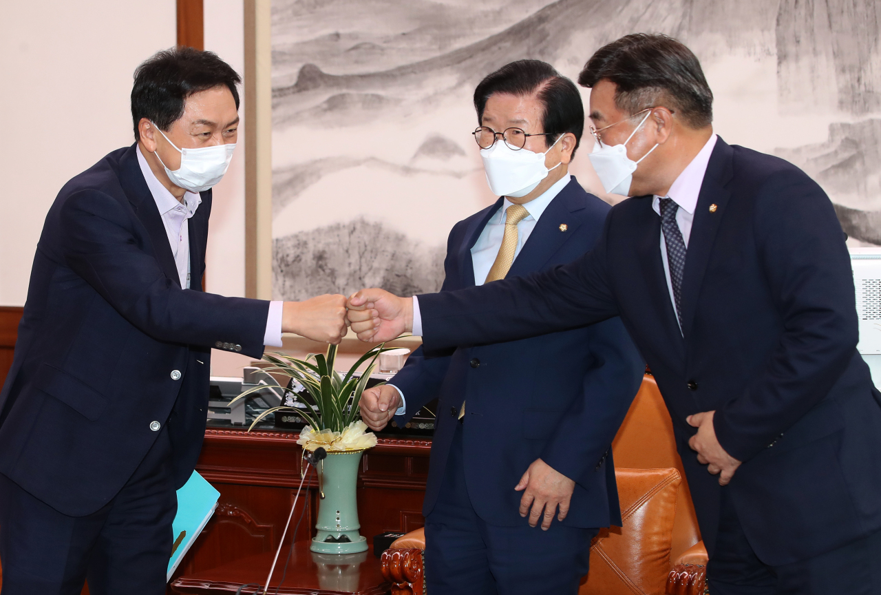 This image distributed by the National Assembly press corps shows Reps. Kim Gi-hyeon (L) and Yun Ho-jung (R), floor leaders of the People Power Party and Democratic Party, respectively, greeting each other during a meeting chaired by National Assembly Speaker Park Byeong-seug on Monday. (National Assembly Pess Corps)