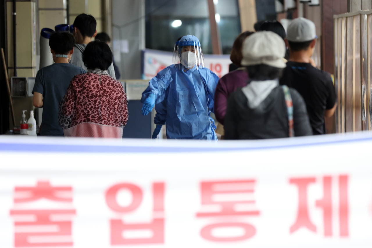 People wait in line to get tested for COVID-19 at a temporary testing center in Seoul on Monday. (Yonhap)