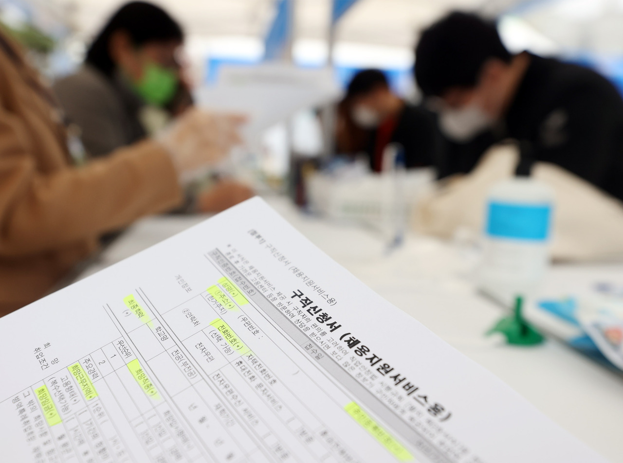 People fill out application forms during a job fair in Seoul earlier this month. (Yonhap)